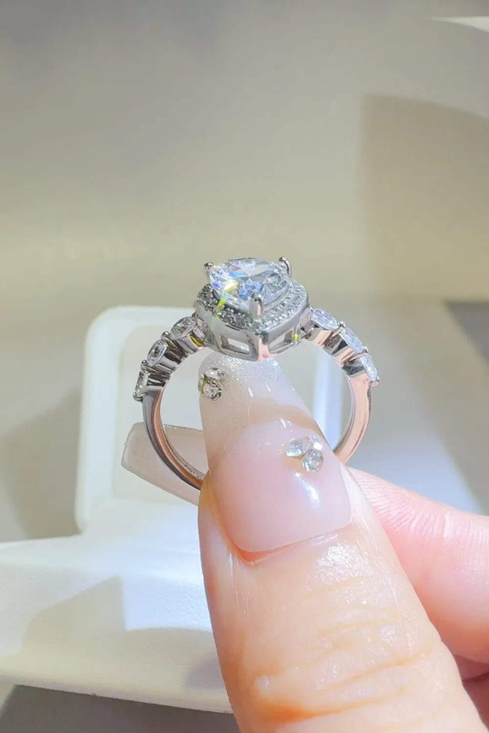 Silver pear-cut halo moissanite ring with accent stones on band