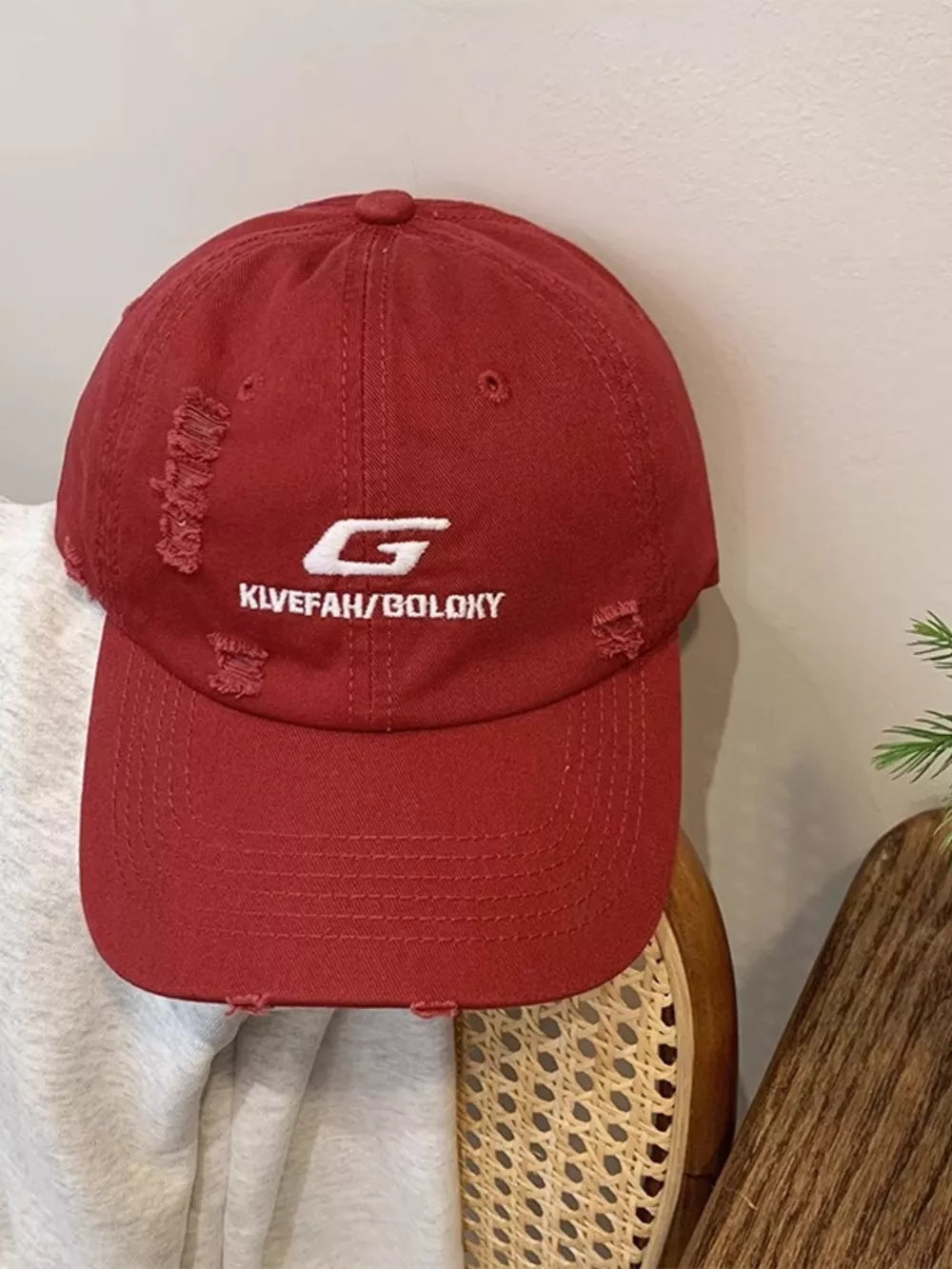 Red cotton baseball hat with distressed details and white embroidery.