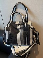 Chic striped medium duffle bag with black and white stripes and a detachable strap.