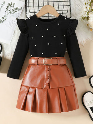 Black ruffled long sleeve top with pearl embellishments and brown faux leather pleated skirt with belt