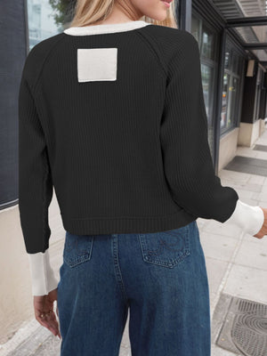 Black knit cardigan with white collar and cuffs, featuring raglan sleeves and a square patch detail on the back.