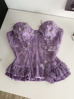 Purple lace bustier top with 3D butterflies, pearl accents, and ruffled hem.