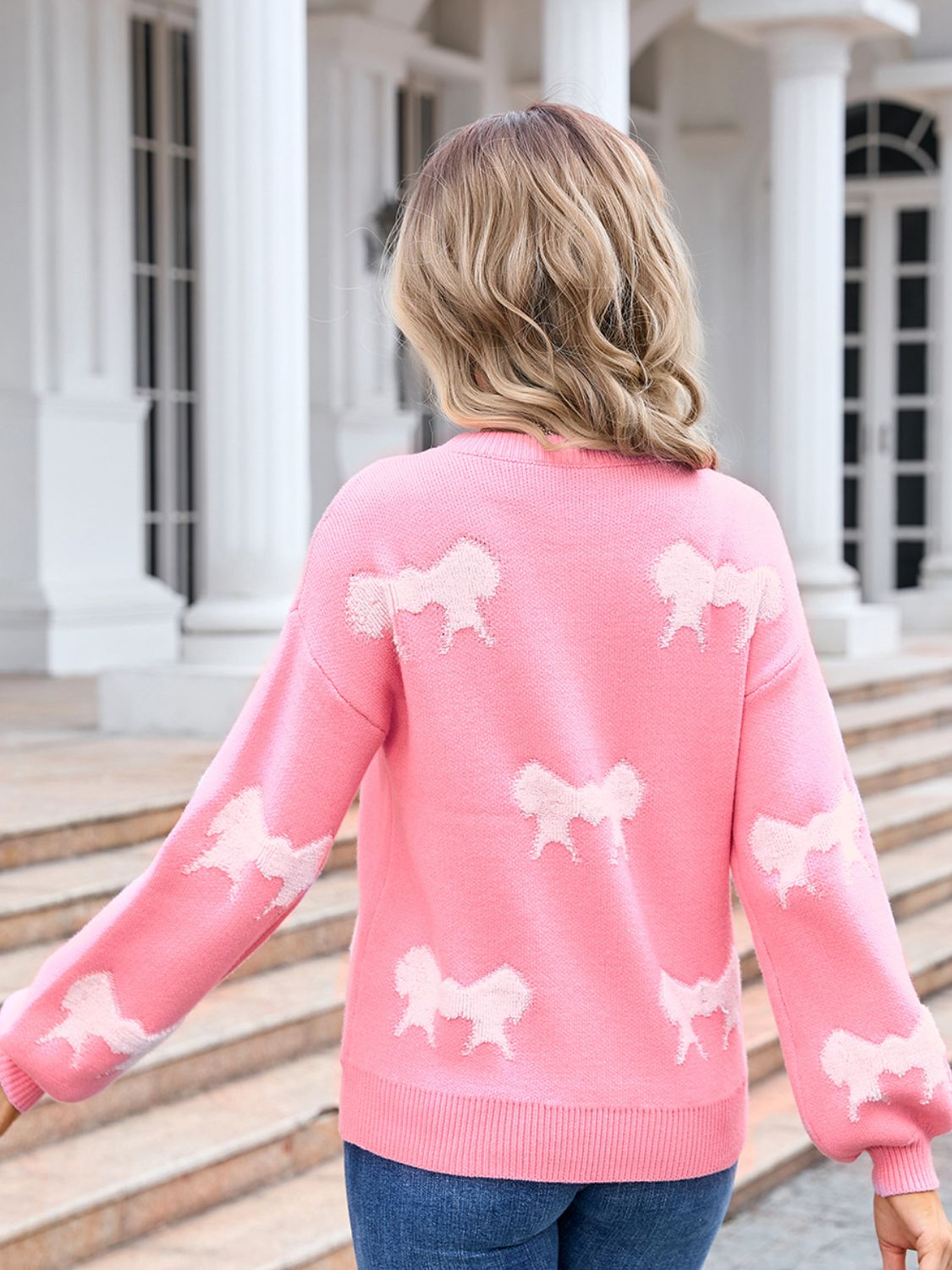 Pink knit pullover sweater with allover bow motif pattern and balloon sleeves.