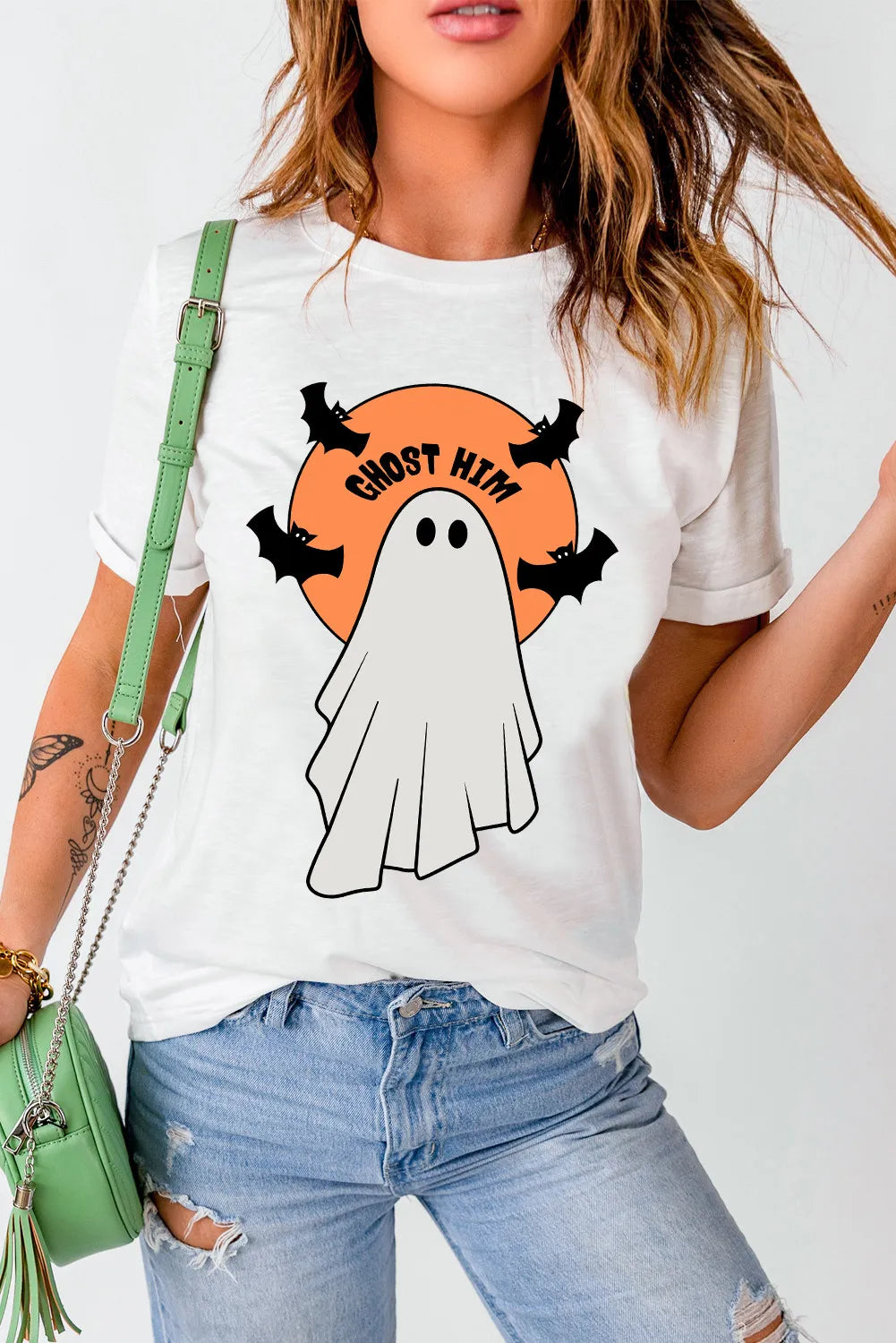 White graphic tee with a ghost, bats, and "Ghost Him" text on an orange circle.