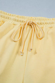 Yellow cotton drawstring pants with elastic waistband and tie detail.