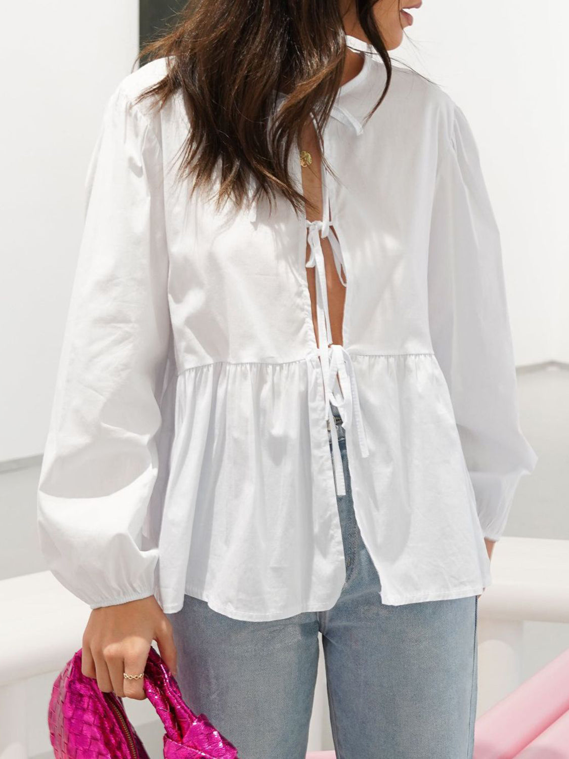 White tie-front peplum blouse with voluminous sleeves and a ruffled hem.