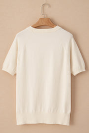 Ivory knit top with short sleeves, crew neck, and daisy appliqué detail.