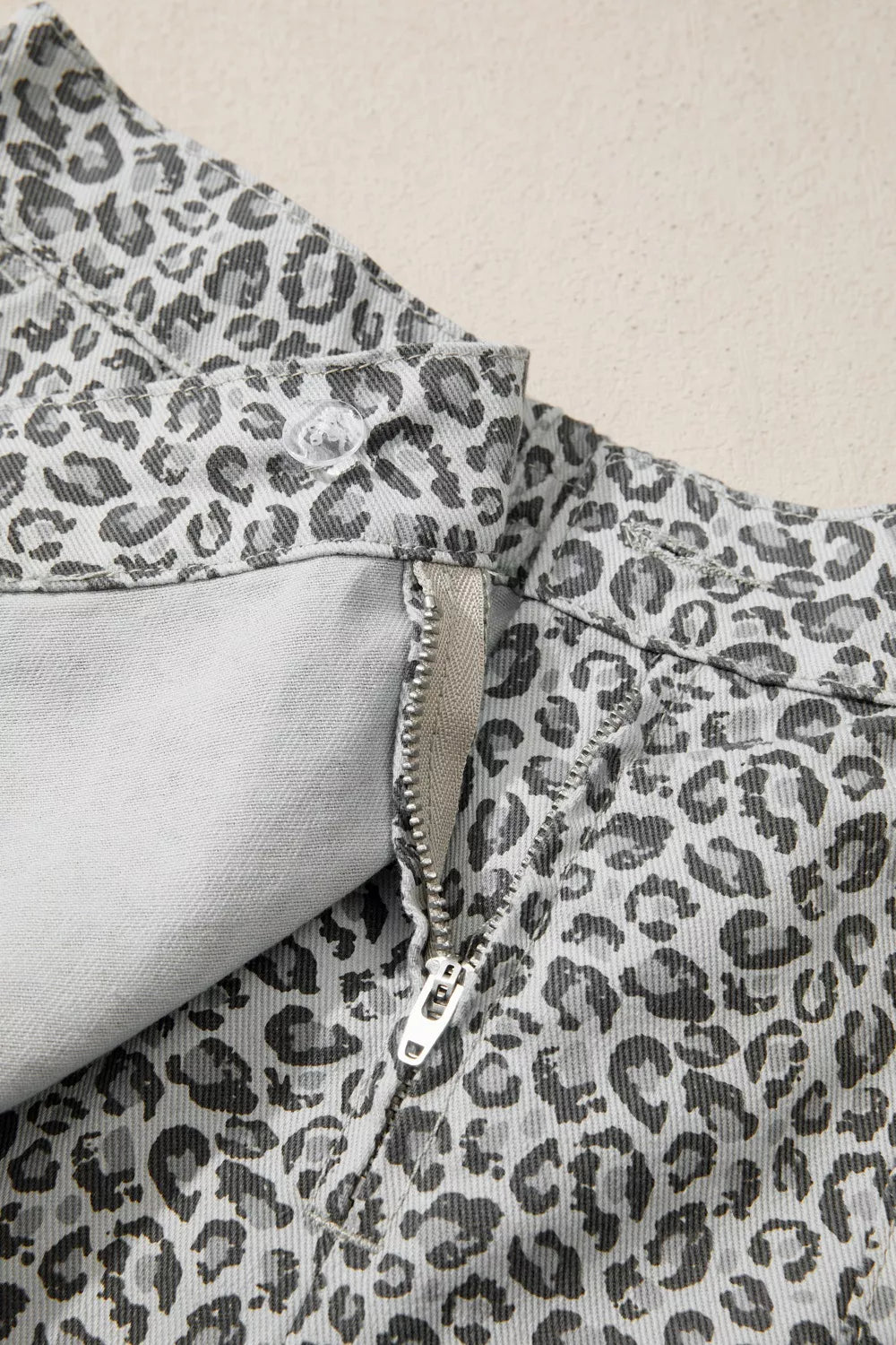 Denim shorts with leopard print, zipper fly, and button closure.