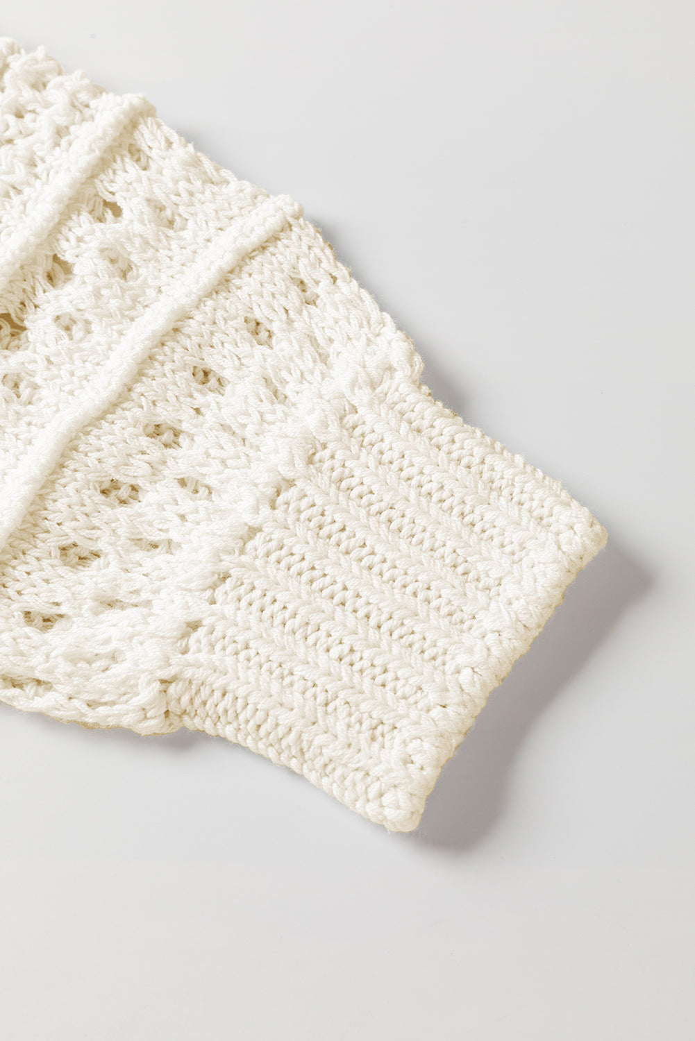 Ivory openwork knit sweater with balloon sleeves and textured details.
