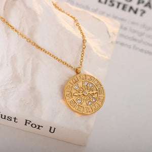 Gold zodiac compass pendant necklace with crystal accents and a celestial design.