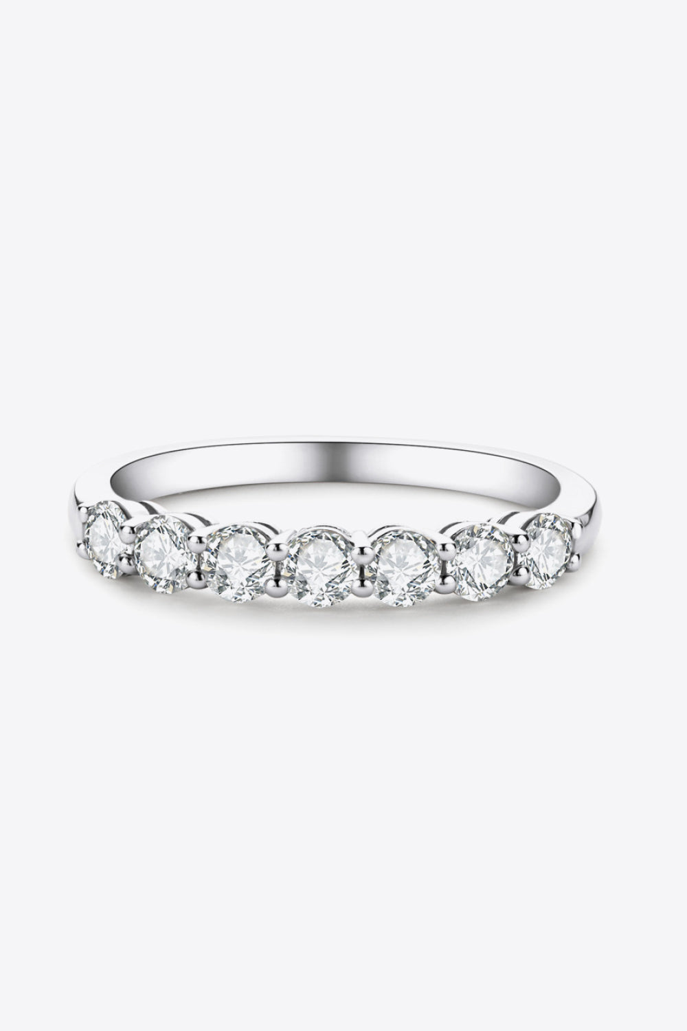 Silver band ring with seven round moissanite stones in a shared prong setting.