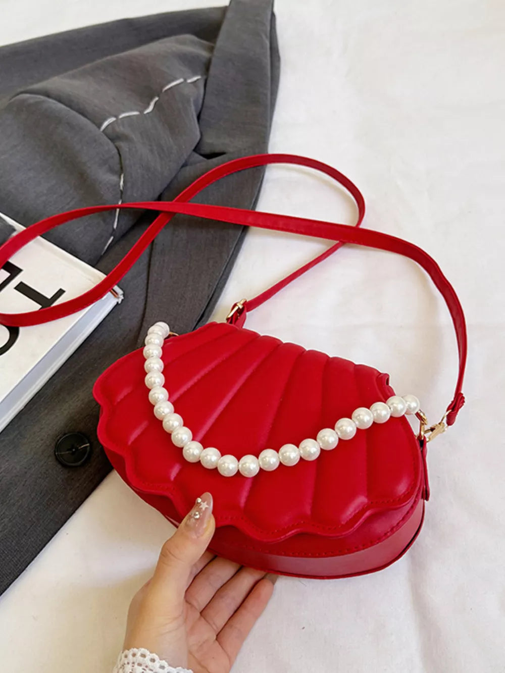 Red shell crossbody bag with pearl strap detail