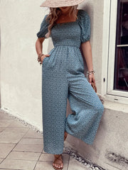 Smocked bodice floral wide-leg jumpsuit in dusty blue with puff sleeves and square neckline.