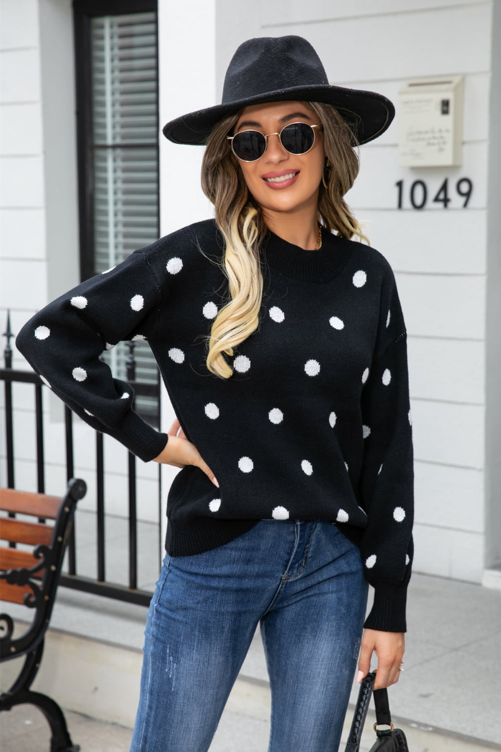Black polka dot knit sweater with balloon sleeves and a crew neck.