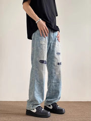 Men's light blue distressed wide-leg jeans with paisley pattern and pocket details.