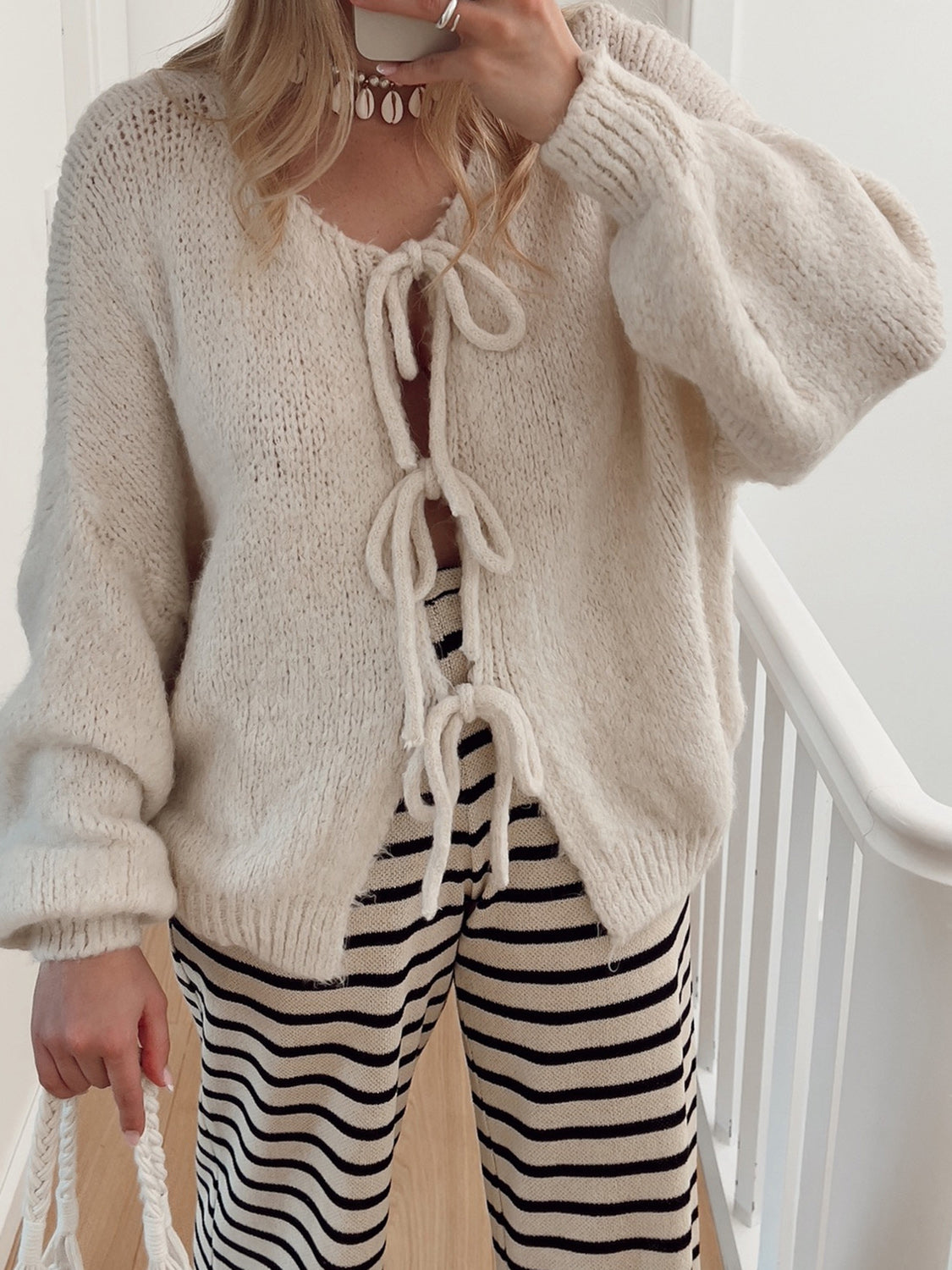 Beige knit cardigan with balloon sleeves and tie front detail.