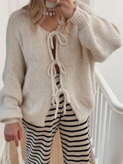 Beige knit cardigan with balloon sleeves and tie front detail.