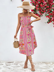 Printed bandeau midi dress with asymmetric hem and belt, featuring a pink, orange, and blue pattern.