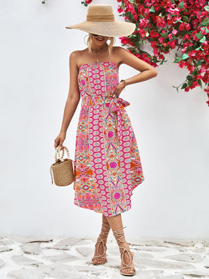 Printed bandeau midi dress with asymmetric hem and belt, featuring a pink, orange, and blue pattern.