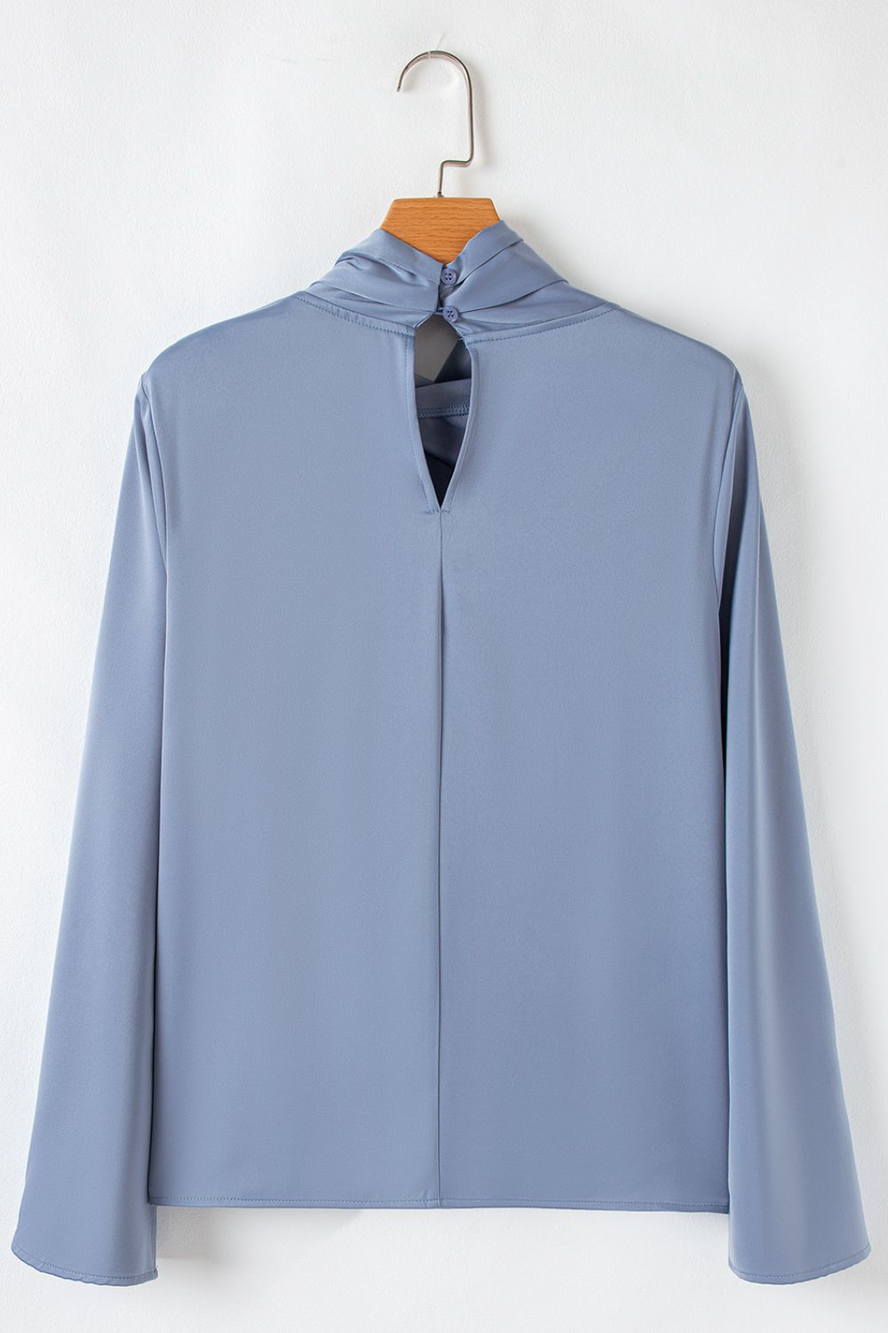Dusty blue blouse with draped neckline, bell sleeves, and back keyhole with button closure.