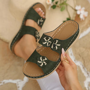 Army green slip-on sandals with floral appliqués and open toe.