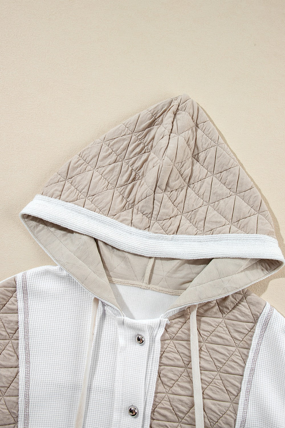 Hoodie with quilted panels and waffle knit fabric, featuring a drawstring hood and button closure.