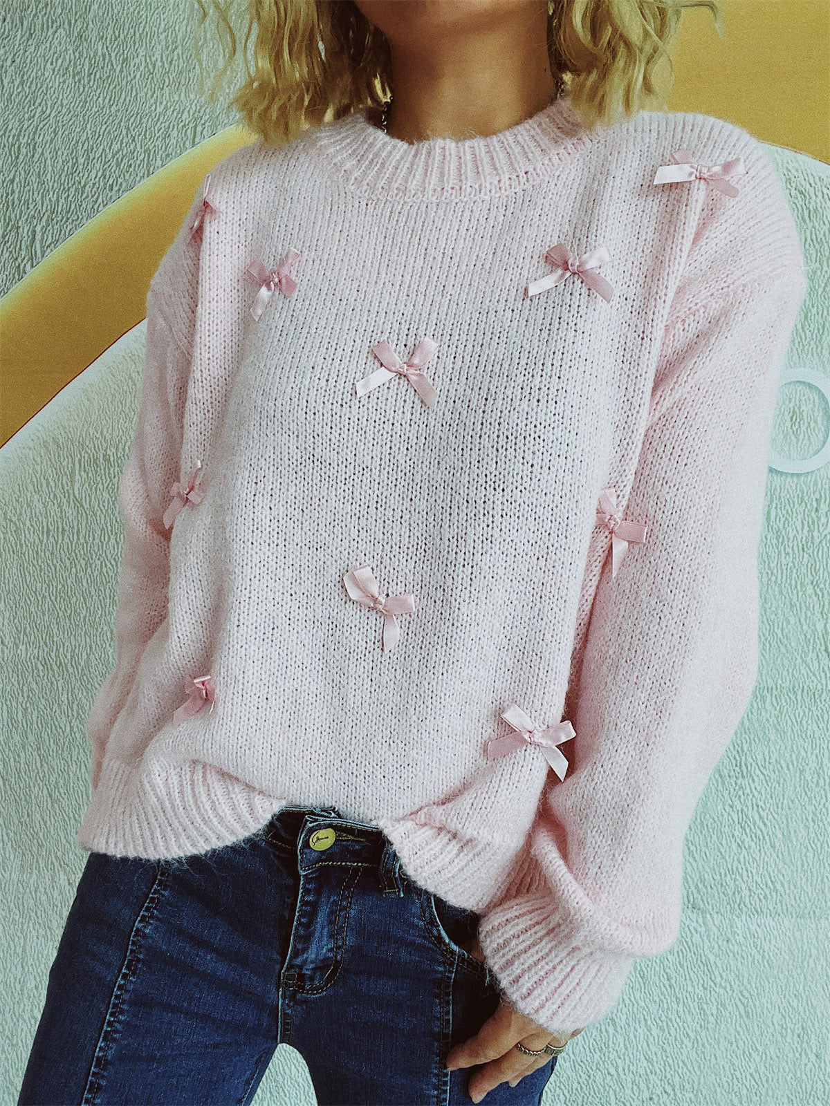Blush pink knit crewneck sweater with allover satin bow embellishments.