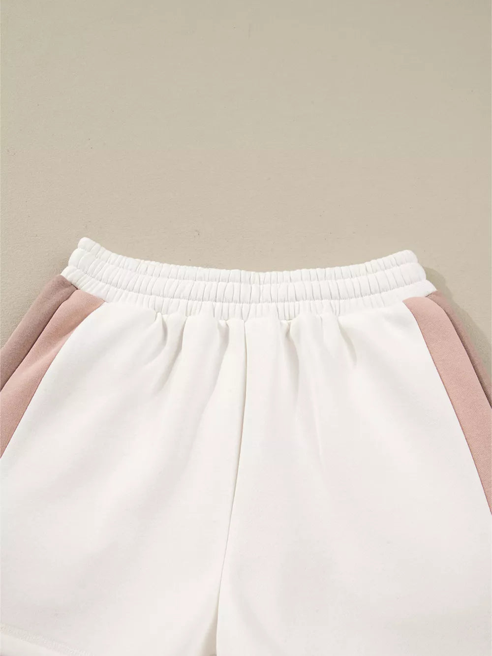 White cotton shorts with blush pink color block detail and elastic waistband.