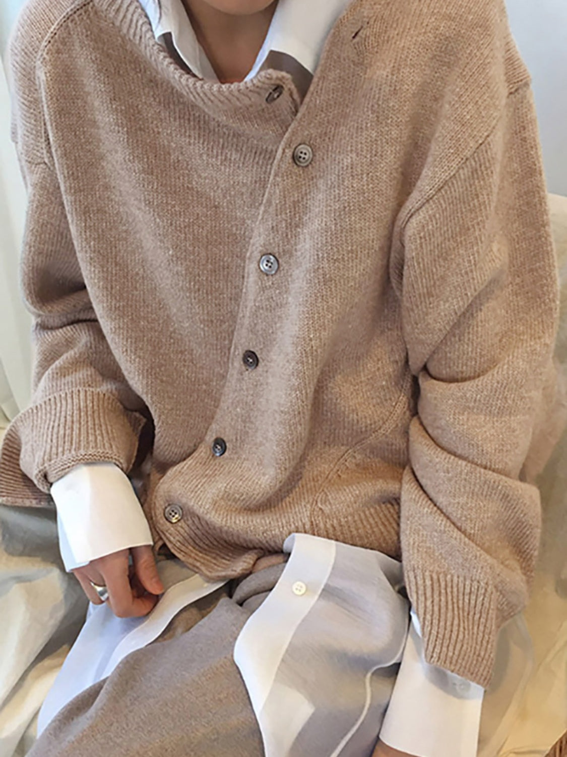 Khaki knit cardigan with asymmetric button front and crew neck, styled with a white shirt.