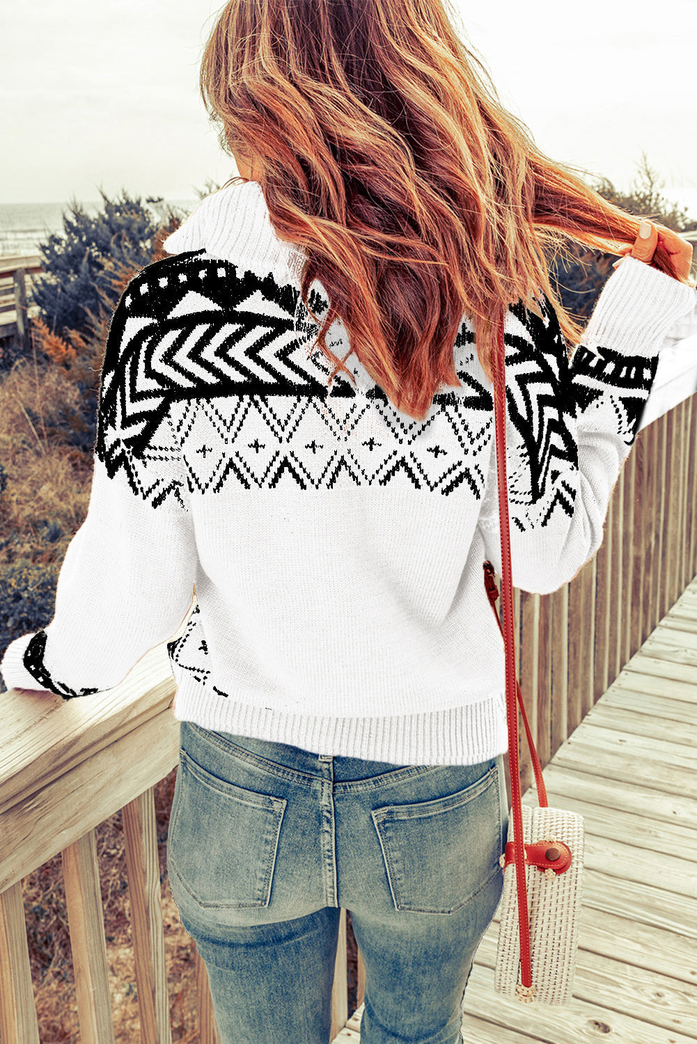 White knit pullover with black geometric pattern and zip neck.