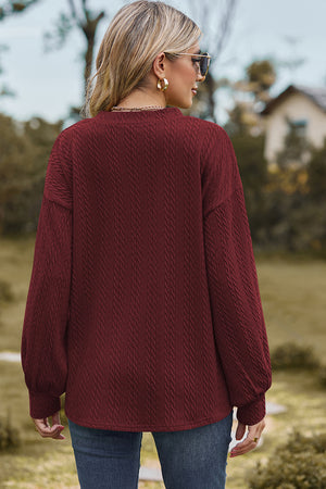 Burgundy cable knit V-neck pullover sweater with textured detail and balloon sleeves.