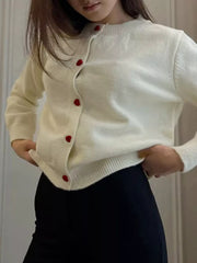 Cream knit cardigan with red heart buttons and crew neck.