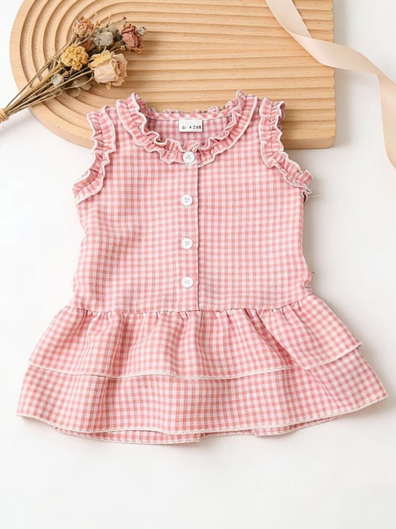 Blush pink gingham baby dress with ruffled neckline and tiered skirt.