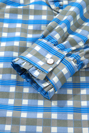 Blue plaid button-down blouse with frilled cuff detail and white button.