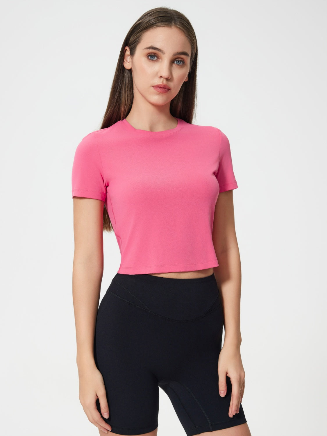 Fuchsia pink cropped performance crew neck top with short sleeves.