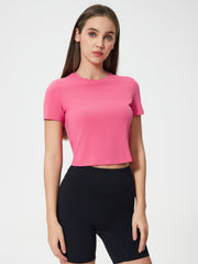 Fuchsia pink cropped performance crew neck top with short sleeves.