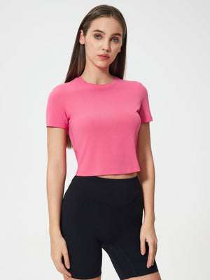 Fuchsia pink cropped performance crew neck top with short sleeves.