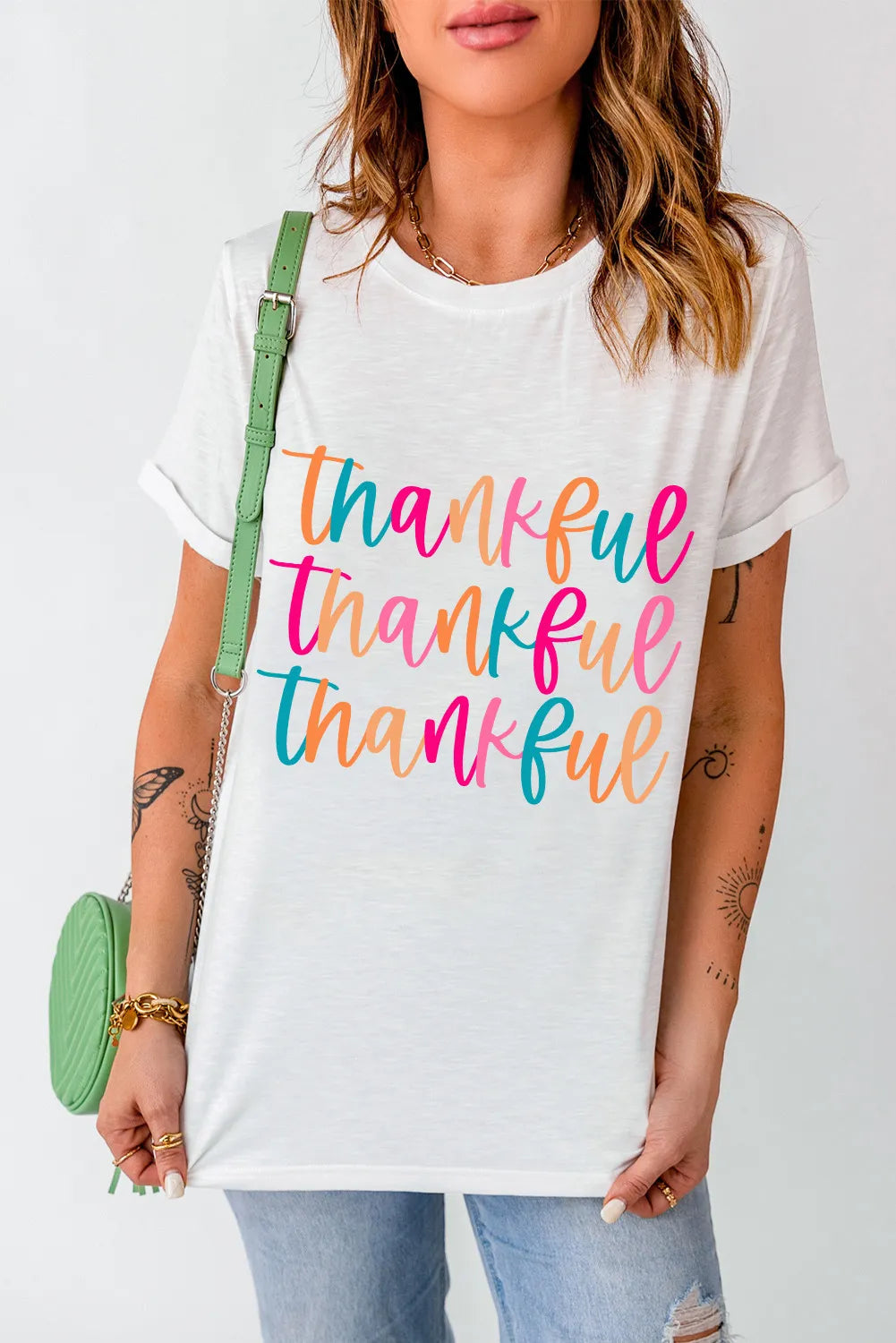 White graphic t-shirt with stacked colorful "thankful" text, crew neck, short sleeves.