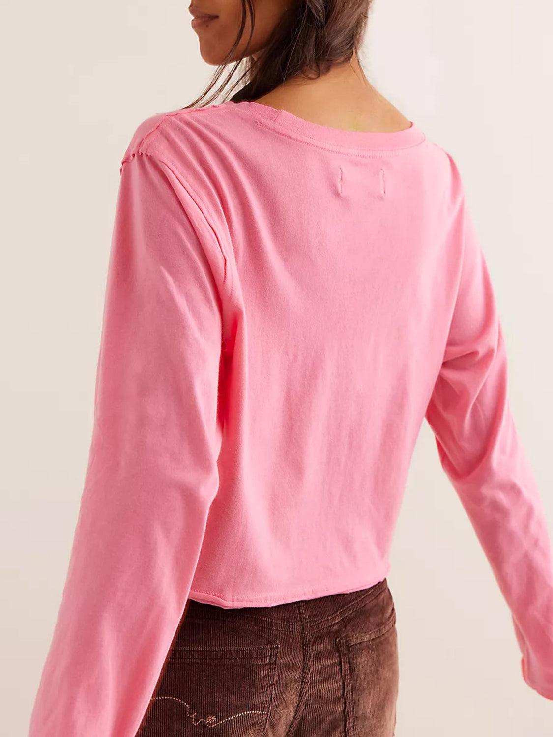 Pink long sleeve crop top with raw hem and crew neck.