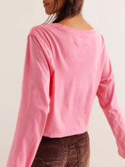 Pink long sleeve crop top with raw hem and crew neck.