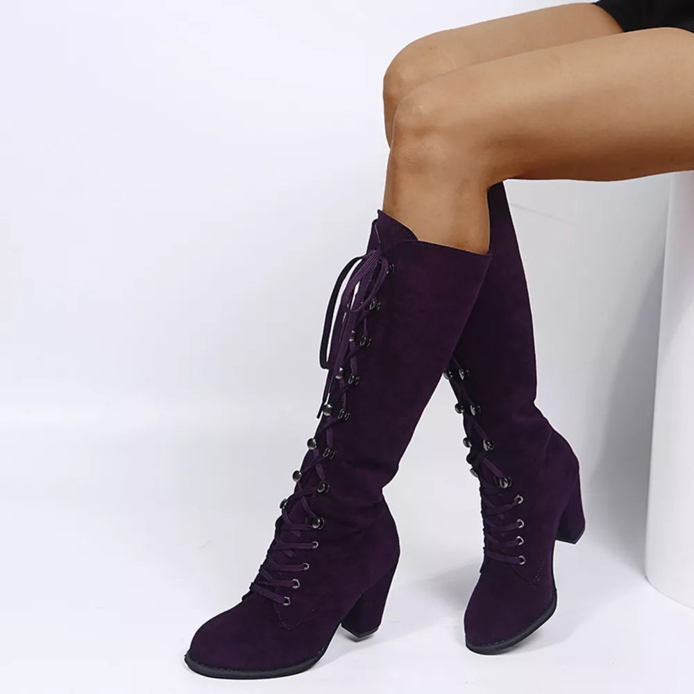 Purple suede lace-up block heel boots with metal eyelets and tie closures.