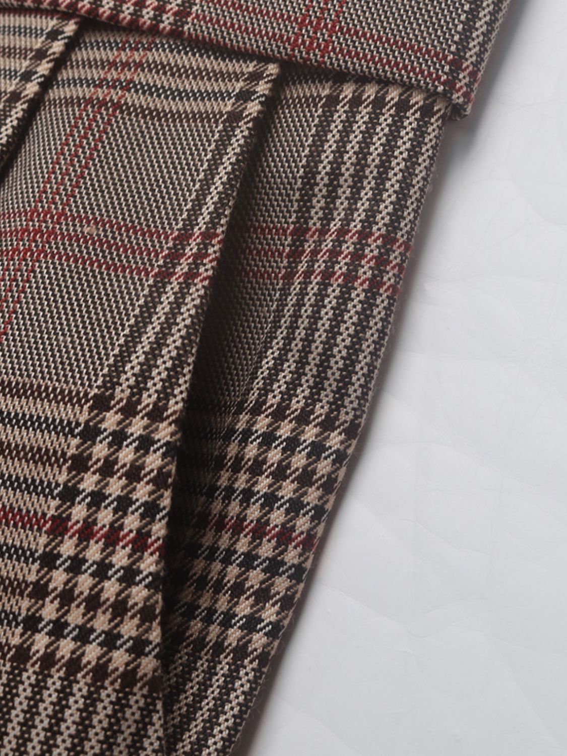 High-waisted taupe plaid trousers with pleat detail and houndstooth pattern.