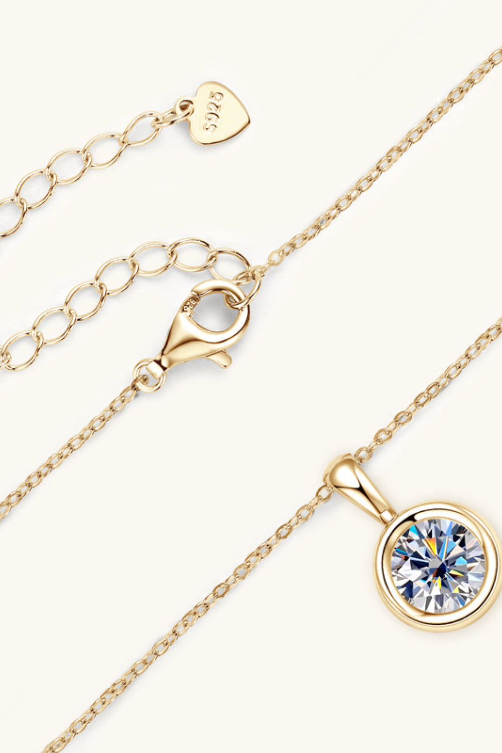 Gold solitaire pendant necklace with bezel-set crystal and adjustable chain with lobster clasp.