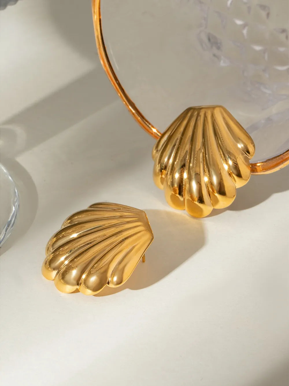 Gold scallop shell stud earrings with a polished finish.