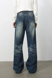 Medium wash denim jeans with distressed details and wide-leg silhouette.