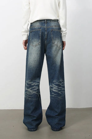 Medium wash denim jeans with distressed details and wide-leg silhouette.