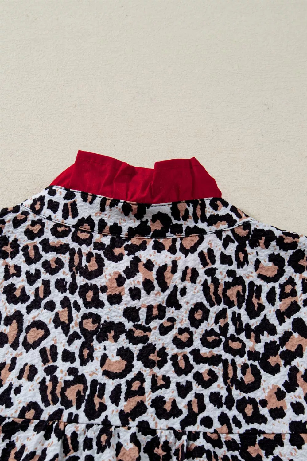 Leopard print polyester shirt with red frilled collar detail.