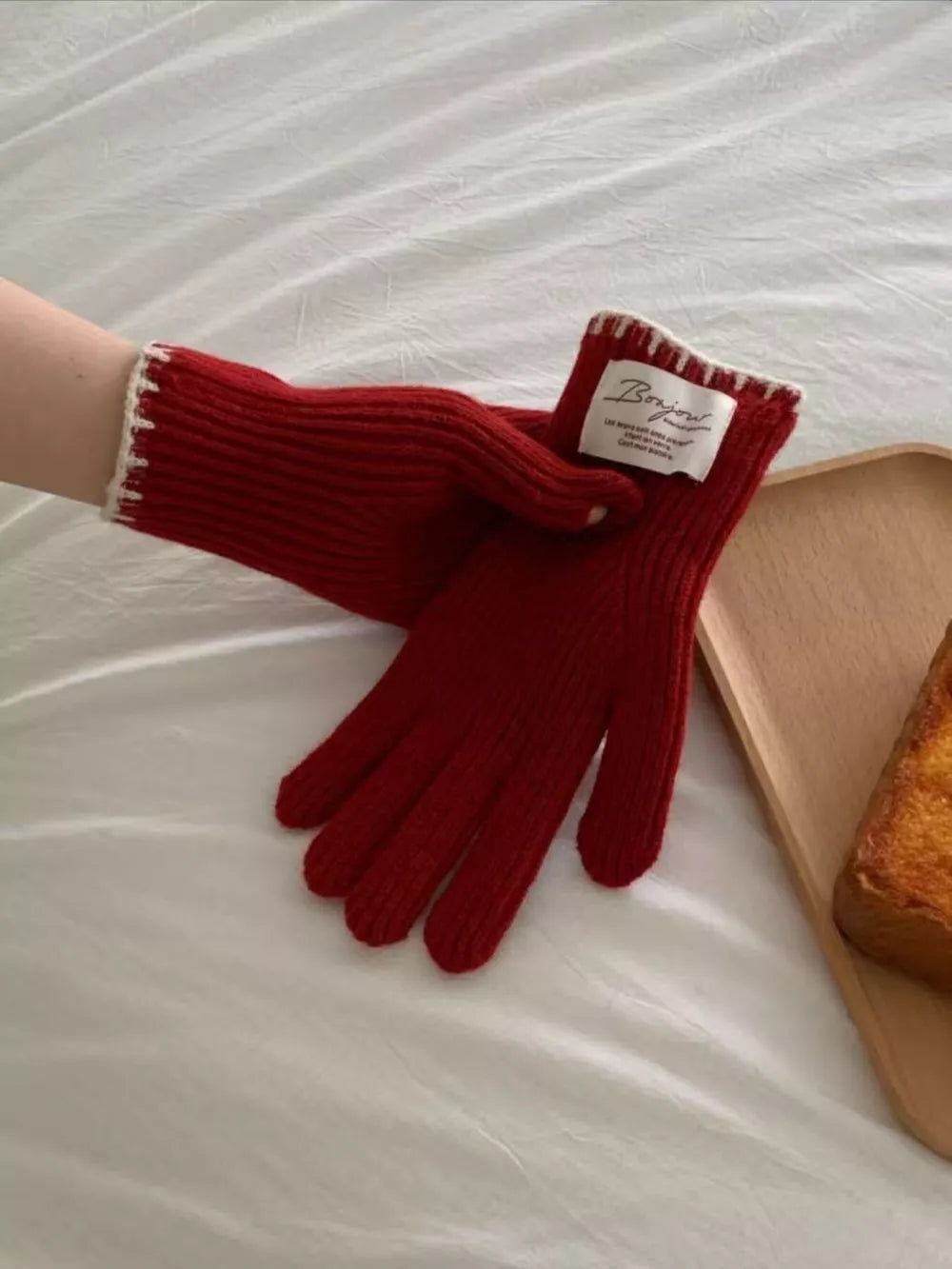 Red ribbed knit gloves with cream scalloped cuff detail and a "Bonjour" tag.