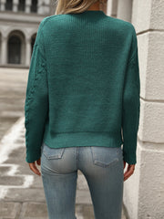 Turquoise cable knit sweater with textured sleeves and crew neck, styled with jeans.