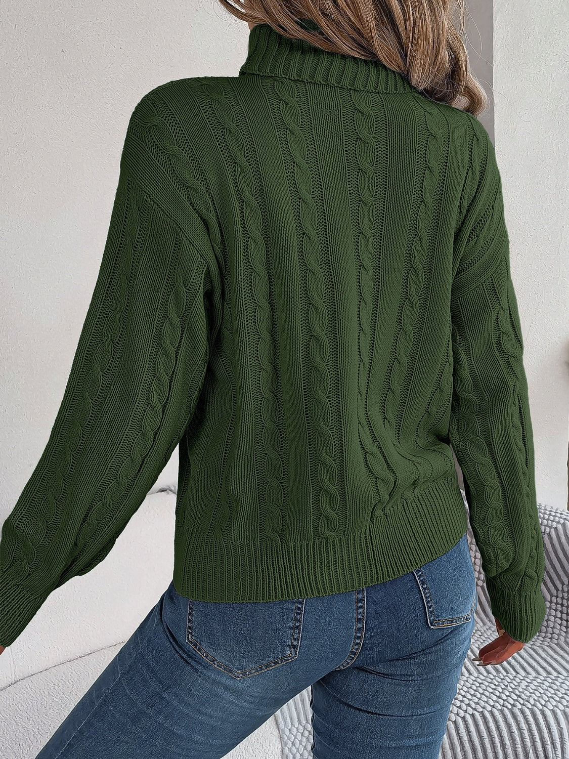 Dark green cable knit turtleneck sweater with voluminous sleeves.